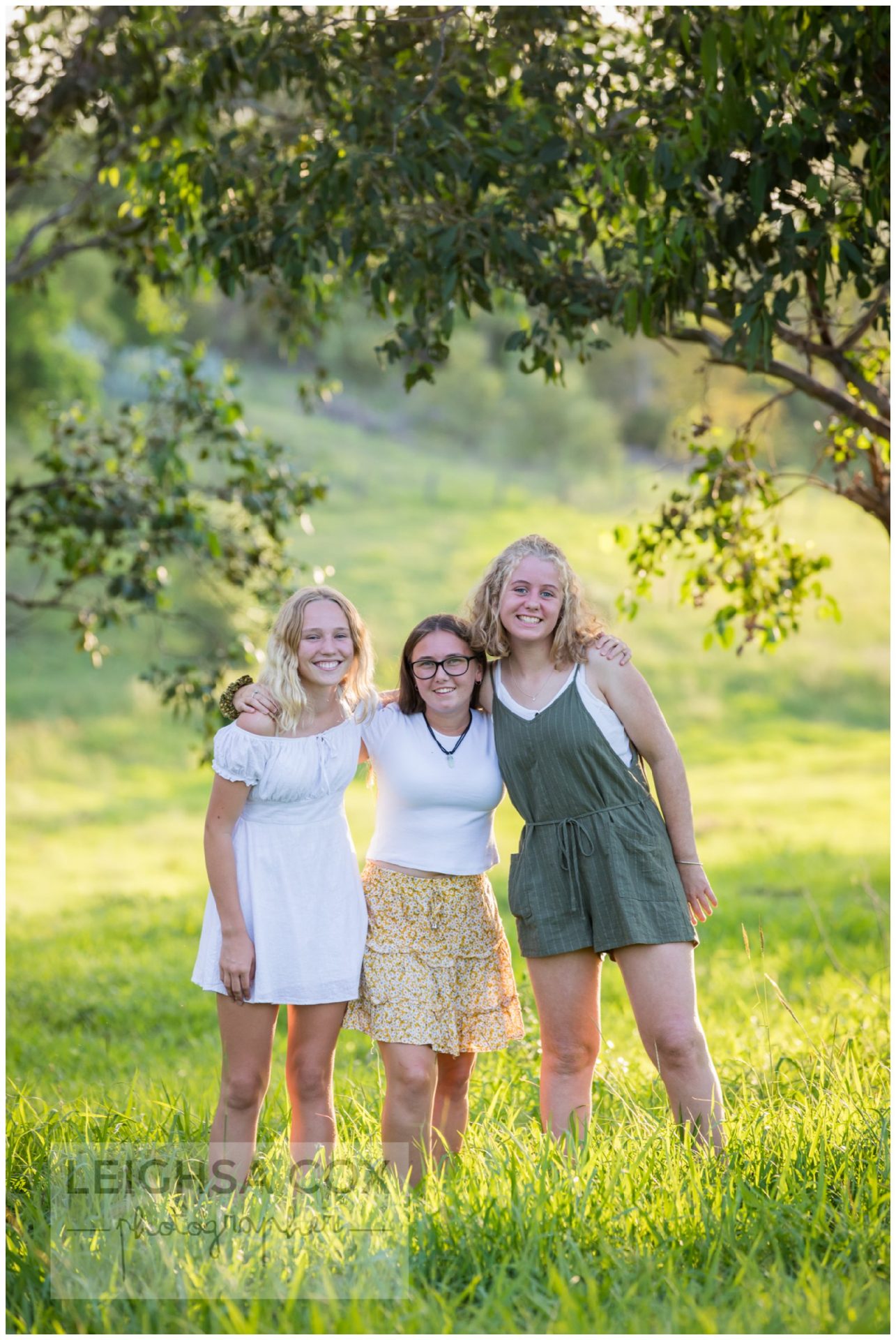 group of three teens in green grass