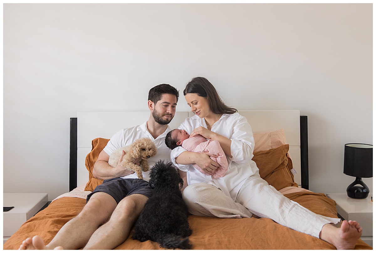 Family newborn cuddles on the bed